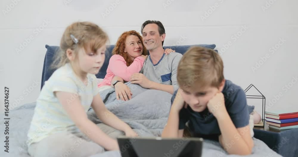 Happy Family Spend Time Together Watching Video On Digital Tablet Computer In Bedroom Children With Parents On Bed In Morning Slow Motion 60 Happy Family Spend Time Together Watching Video On Digital Tablet Computer In Bedroom Children With Parents On Bed In Morning Slow Motion 60