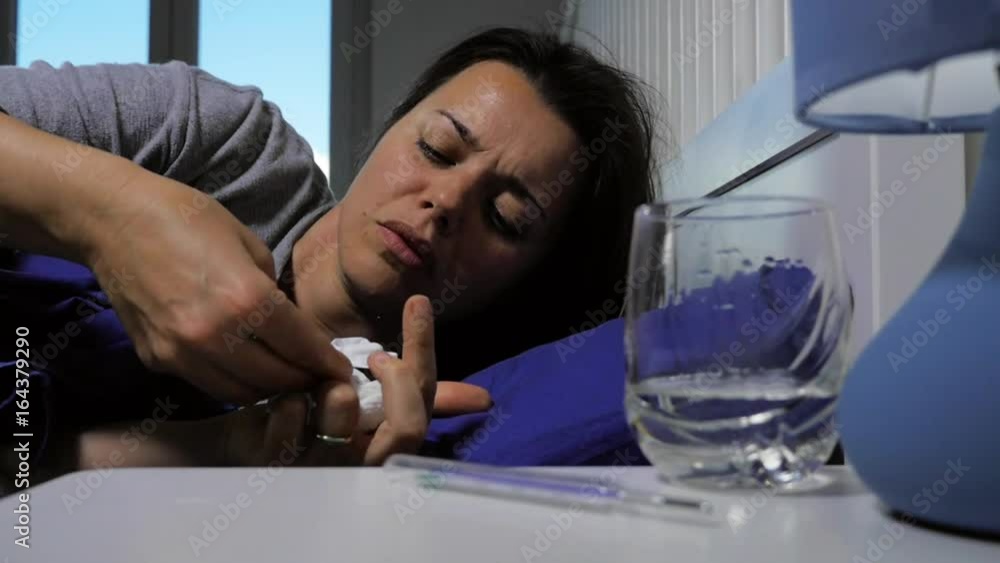 Sick woman in bed taking pill slow motion Sick woman in bed taking pill slow motion