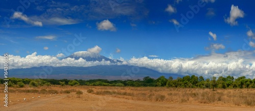 Kilimanjaro mountain Tanzania snow capped under cloudy blue skies captured whist on safari in Africa Kenya. photo