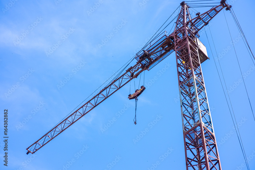 Construction site in the city, crane and the incomplete building on blue sky Construction site in the city, crane and the incomplete building on blue sky