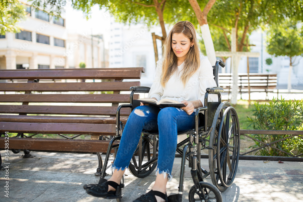 Woman in wheelchair reading at a park