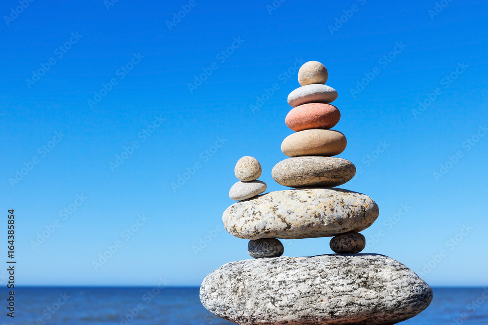 Stones balance on a background of blue sky and sea Stones balance on a background of blue sky and sea