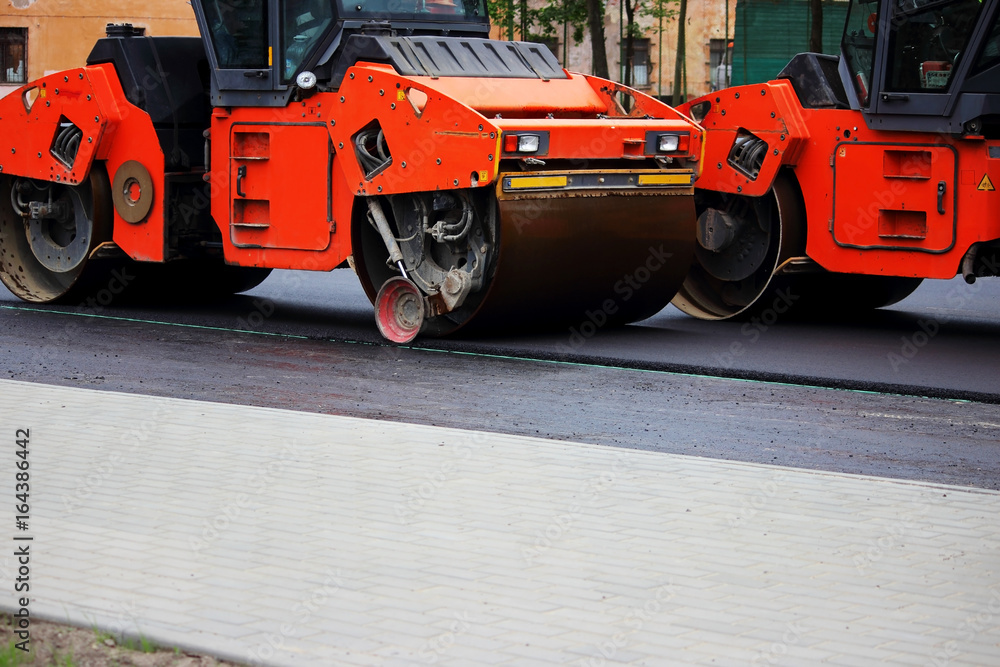 Φωτογραφία Two heavy compactor tires the upper layer of asphalt in the construction of a parking lot for tourist buses