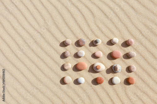 Pattern of colored pebbles on clean sand. Zen background, harmony and meditation concept
