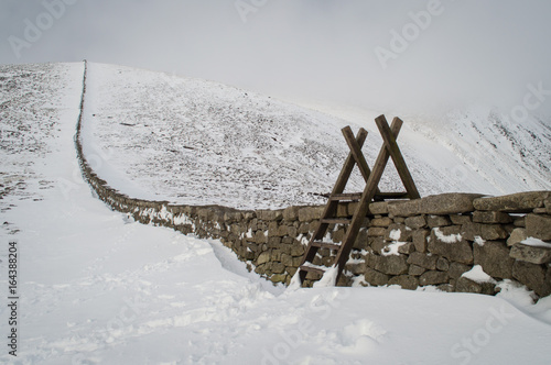 Stile over stone wall in snowy landscape