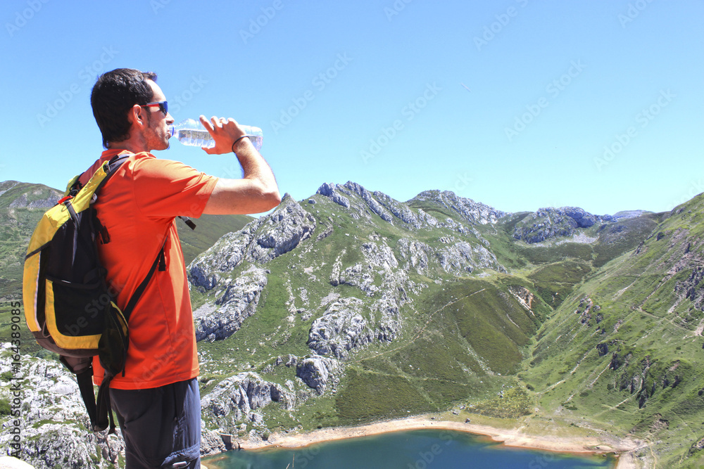 man drinking water in front of a Saliencia's lake in Asturias, Spain