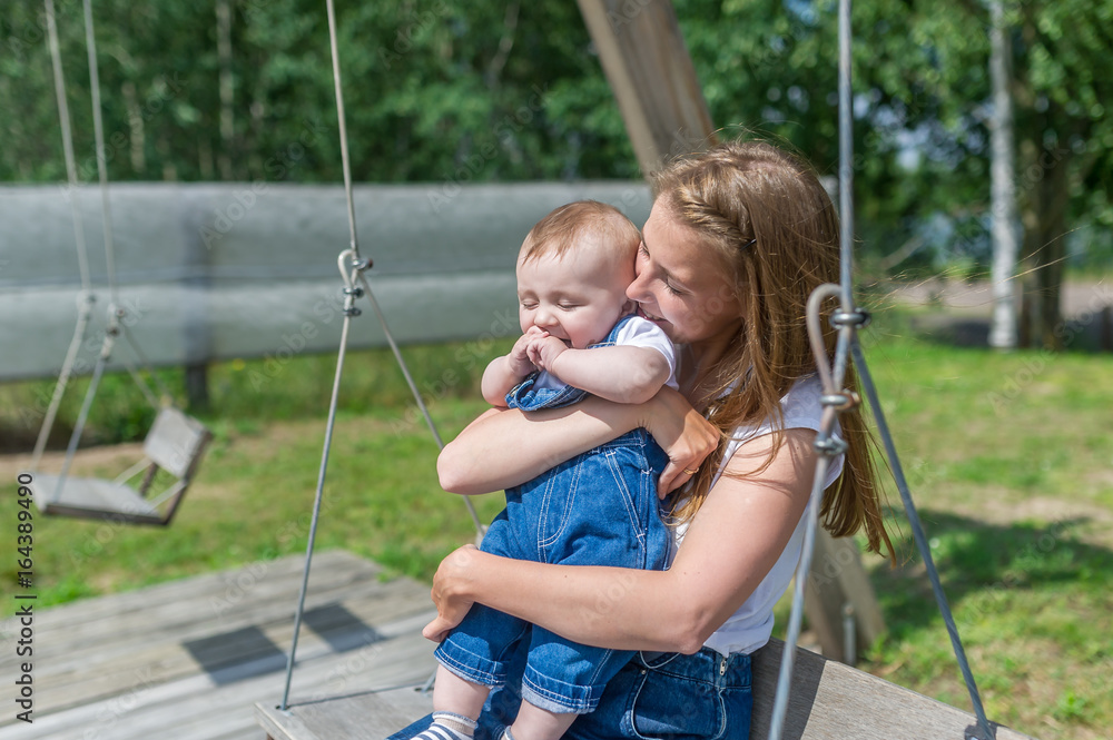 Happy mother and laughing son on swing in a park Happy mother and laughing son on swing in a park