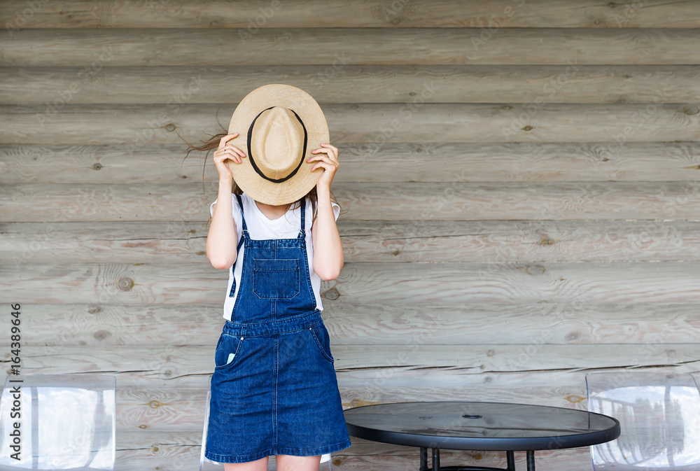 Fototapeta premium Young girl with hat. Hides her face.