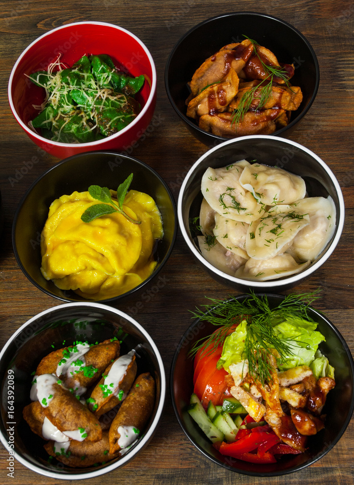 Set of different salad, dumplings and ravioli on a wooden table Set of different salad, dumplings and ravioli on a wooden table