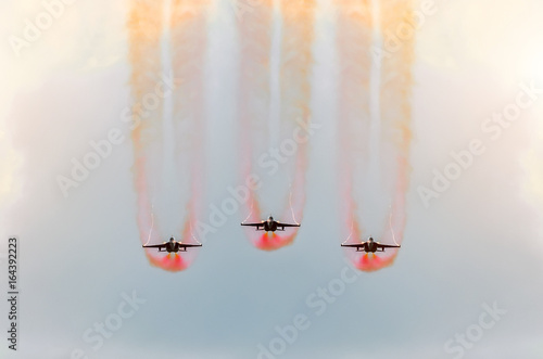 Fotografie Two fighter jets fly together with red smoke