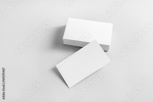 Photo of blank business cards with soft shadows on paper background. Mockup for branding identity. Studio shot.