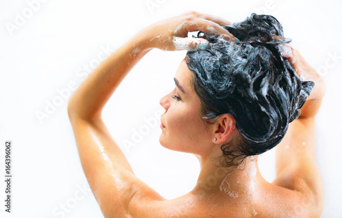 Beauty sexy model girl taking shower and washing her long black hair with a shampoo