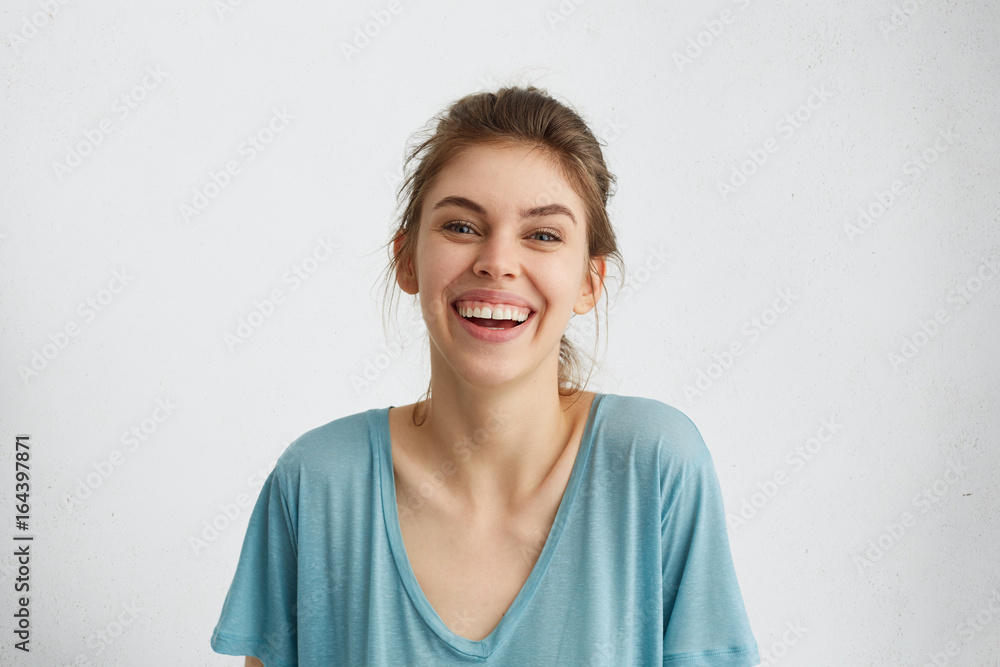 Portrait of glad woman with blue eyes smiling in camera sincerely rejoicing her future wedding with boyfriend. European woman with broad smile in blue casual blouse posing against white background Portrait of glad woman with blue eyes smiling in camera sincerely rejoicing her future wedding with boyfriend. European woman with broad smile in blue casual blouse posing against white background