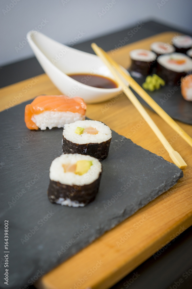 Sushi on a wooden table on black slate plate with soy sauce and chopsticks Sushi on a wooden table on black slate plate with soy sauce and chopsticks