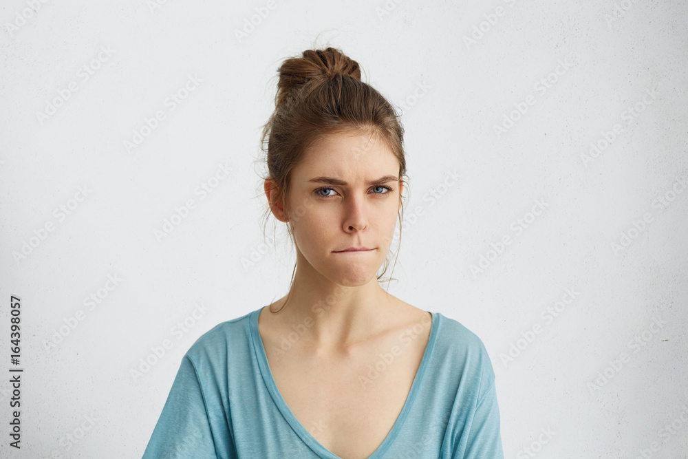 Serious angry woman frowning her face pressing lips togehter with anger trying to control herself and her emotions not showing her annoyance and anger. Dissatisfied young female in casual clothes Serious angry woman frowning her face pressing lips togehter with anger trying to control herself and her emotions not showing her annoyance and anger. Dissatisfied young female in casual clothes