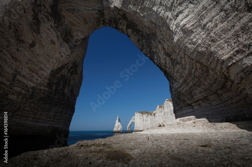 Looking through the Manneporte arch towards the Porte d'Aval and L'Aiguille at Etretat, a commune in the Seine-Maritime department in the Normandy region of north western France