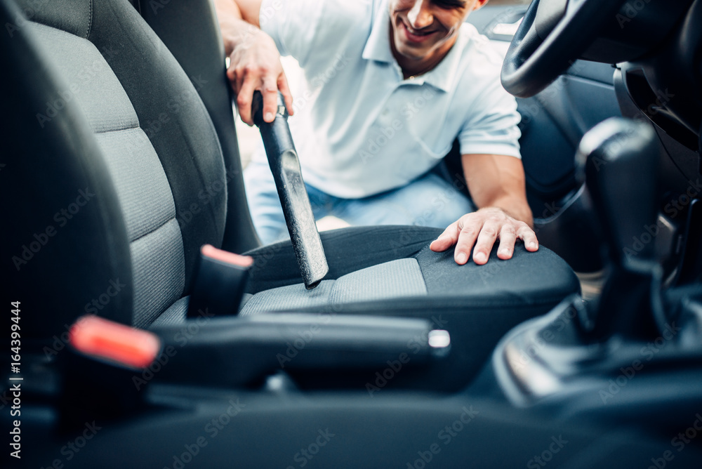 Man cleans car interior with vacuum cleaner