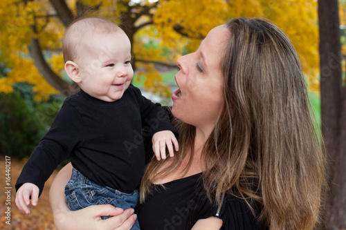 Portrait out of doors of mother and smiling baby  mother holding baby and talking  to her. 