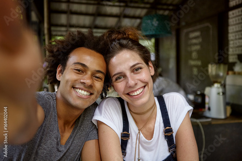 фотографія Positive friendly male and female from different countries rejoicing their meeting at cafe spending free time making photos of themselves having good mood