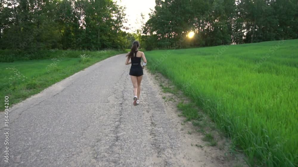 Young woman runner is running down the road in a sporty uniform Young woman runner is running down the road in a sporty uniform