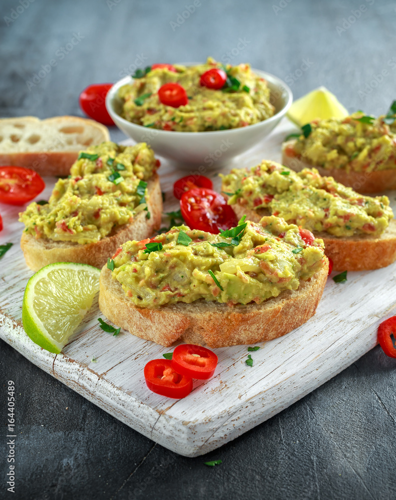 Homemade Guacamole toast with chili pepper, parsley on white wooden board