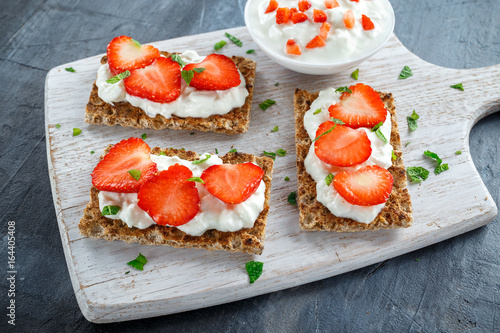 Homemade Crispbread toast with Cottage Cheese and Strawberry on white wooden board.