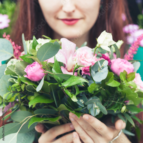Street portrait of a young serene girl with a bouquet of flowers.