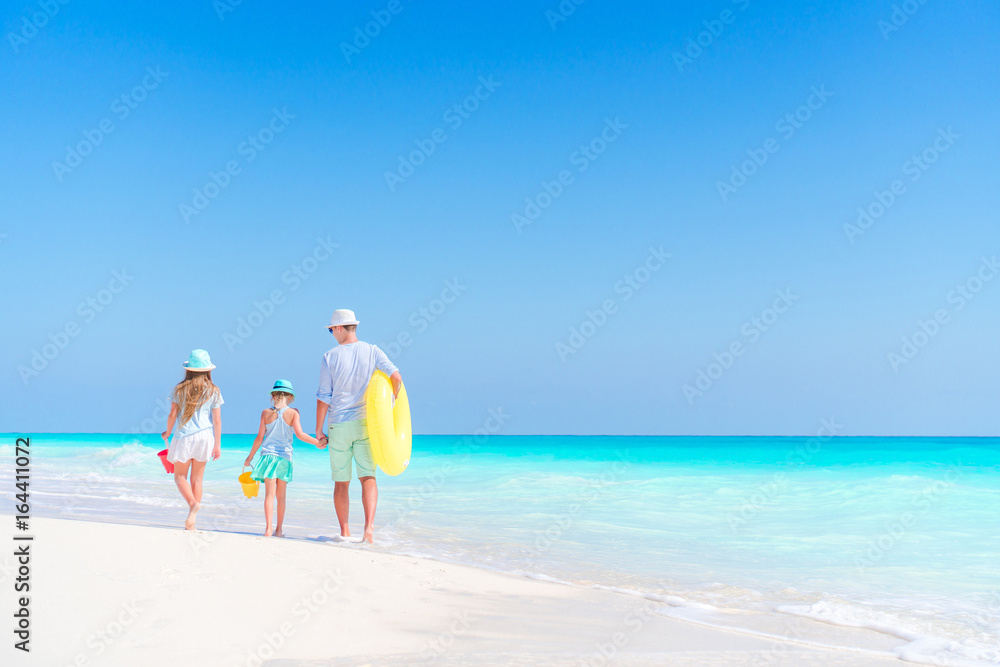 Family of dad and kids walking on white tropical beach on caribbean island