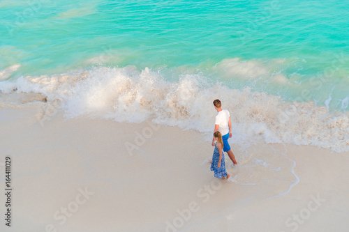 Little adorable girl and young faher at tropical beach with turquoise view from above photo