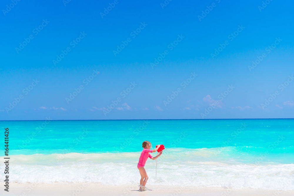 Little girl play with beach toys during tropical vacation