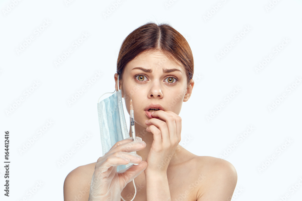 Beautiful young woman on white isolated background holds a syringe, medicine, plastic Beautiful young woman on white isolated background holds a syringe, medicine, plastic