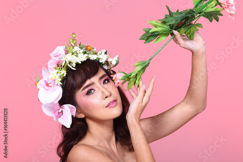 Beautiful Asian Woman black hair with flora crowd  holding bouquet artificial rose over chest