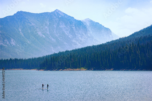 Mountain Lake Recreation. Paddle boarders drift through the Hyalite Reservoir in Montana. Majestic copy space. © boundlessimages
