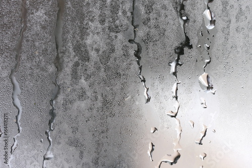 Detailed texture of water dripping down glass in a humid room. photo