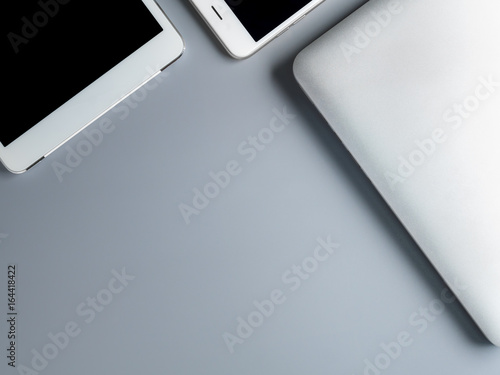 Flat lay and minimalist image of laptop, smartphone and tablet on gray background with copy space