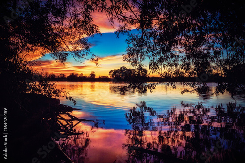 River Sunset Reflections. Tranquil Riverside Silhouette with Glowing Copy Space.