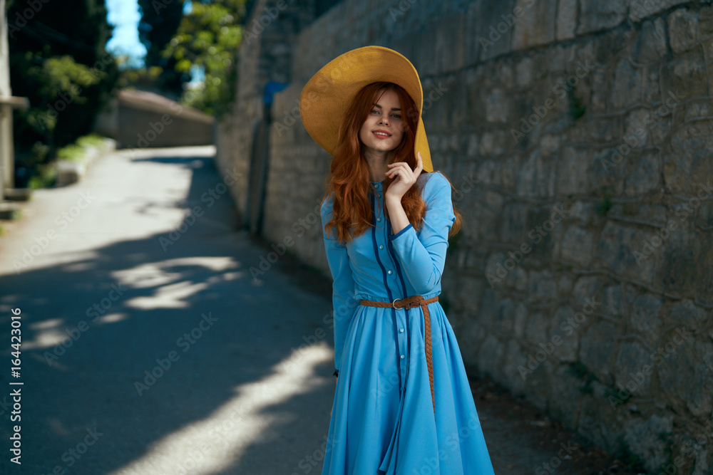 Beautiful young woman in blue dress walking along the street