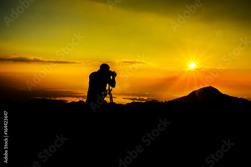 silhouette of photographer on the top of mountain takephoto to sunset river clounds sky view, Thailand photo