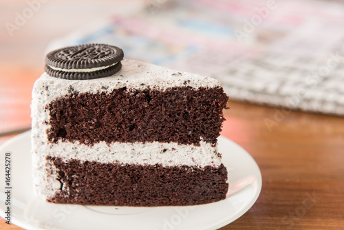 Chocolate Cake with oreo and whipped cream on white plate and wood table has ready to served. photo