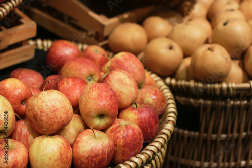 Apples in the basket lay beside Chinese pear in supermarket.