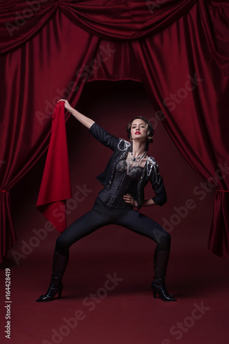 Art photo of fashion young woman on stage with red curtains.