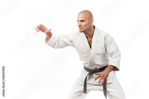 Young man fighter in a white kimono with black belt for judo, jujitsu pose on isolated white background