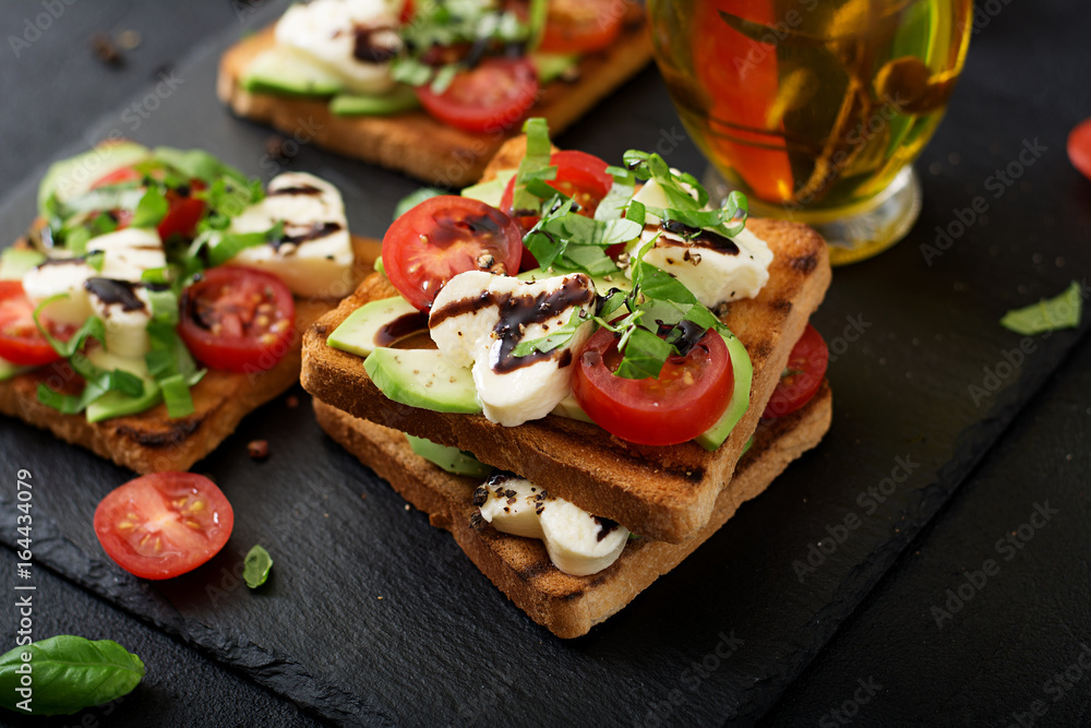 Sandwich toasts with tomatoes, mozzarella, avocado and basil with balsamic vinegar. Sandwich toasts with tomatoes, mozzarella, avocado and basil with balsamic vinegar.