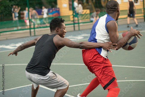 African american man friends playing on basketball court. Real authentic activity.