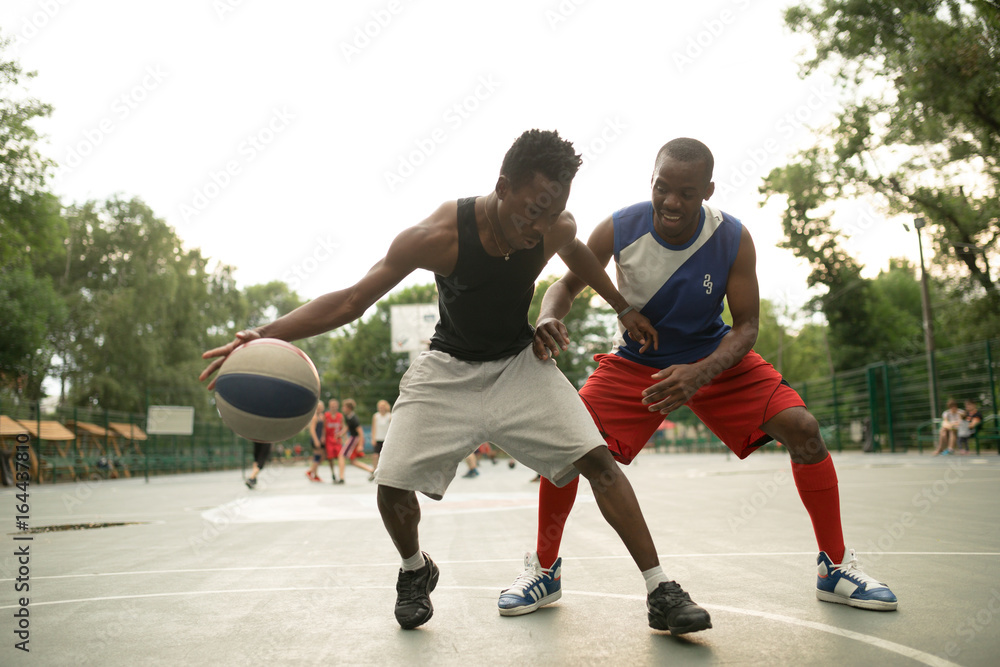 African american man friends playing on basketball court. Real authentic activity.