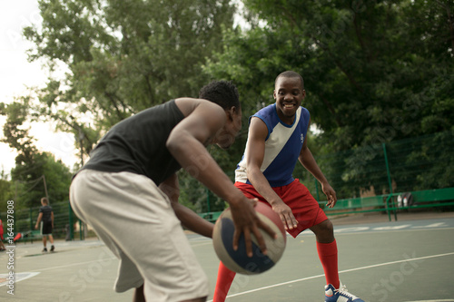 African american man friends playing on basketball court. Real authentic activity.