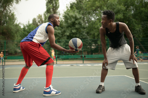 African american man friends playing on basketball court. Real authentic activity.