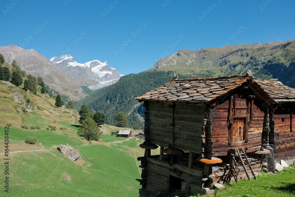 Typical old Swiss wooden huts with view on Monterosa massif, near Zermatt.