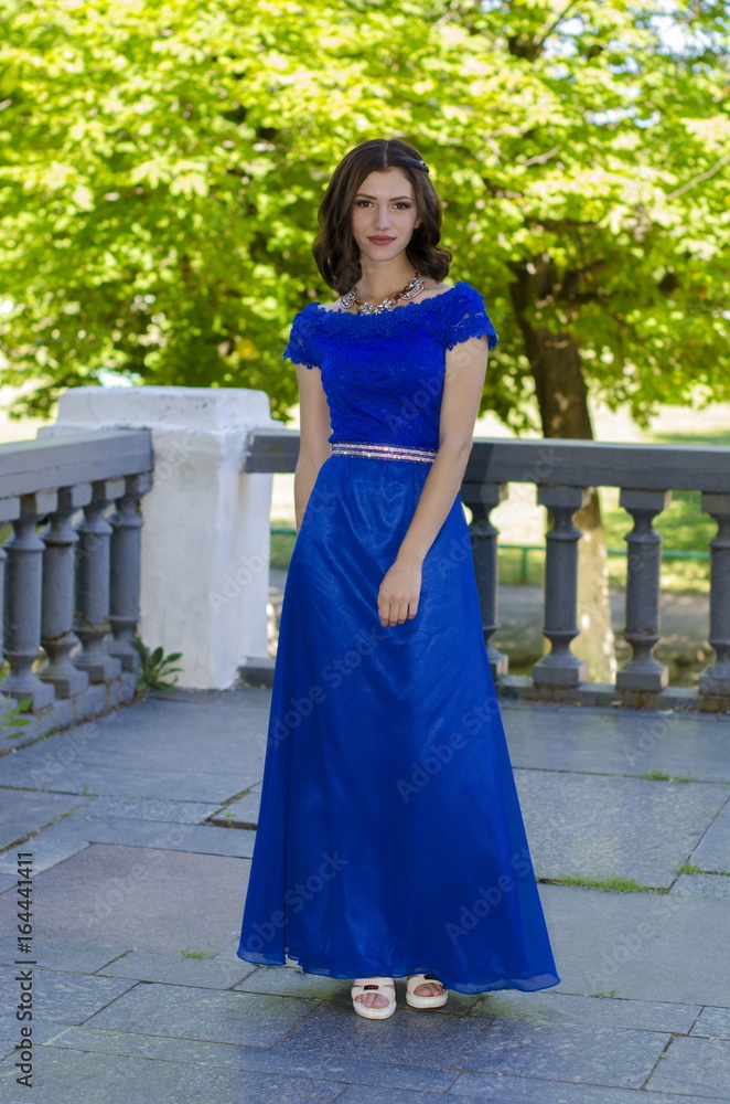 Beautiful girl in a blue dress posing against a background of massive handrails.
Beautiful girl in a blue dress posing against a background of massive handrails.