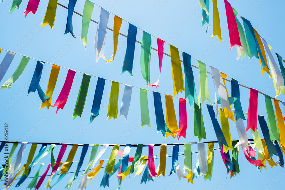 colorful bunting flags against a blue saturated sky colorful bunting flags against a blue saturated sky